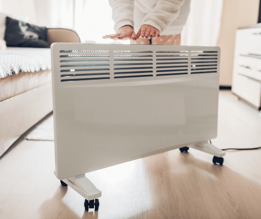 Image of a person holding their hands over a space heater at home